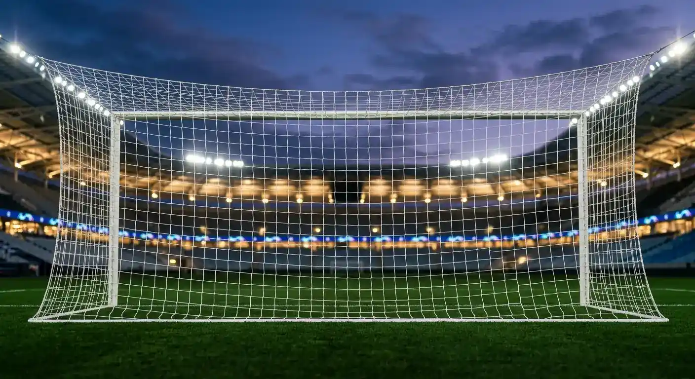 Ett fotbollsmål med nät i förgrunden och en upplyst arena i bakgrunden